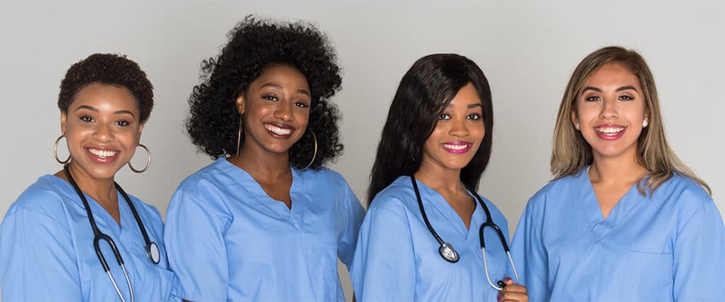 Group of nurses smiling and wearing blue scrubs